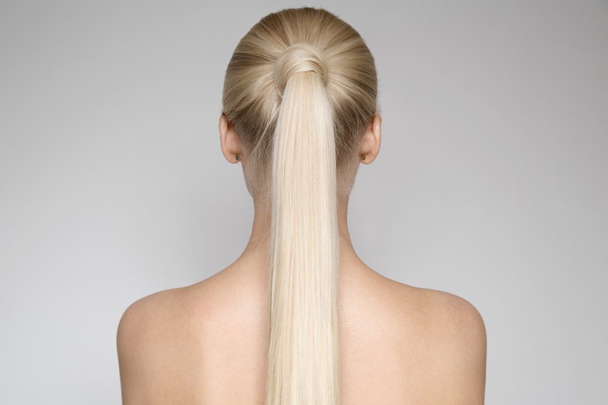 Back of a blonde woman's head with hair wrapped around ponytail like a bobble