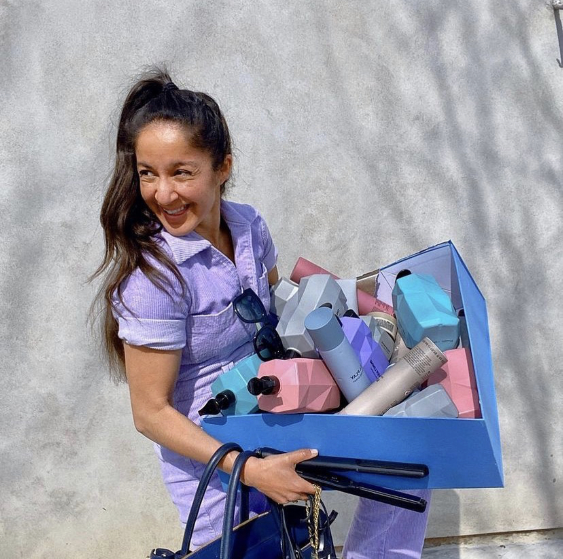 A woman carrying a handful of Nine Yards hair products