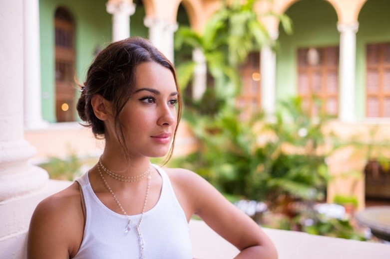 A person in a white tank top with hair in a bun